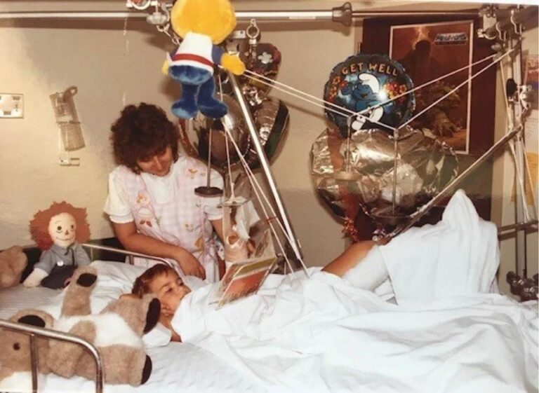 Kelly English as a child in a hospital room with nurses taking care of him